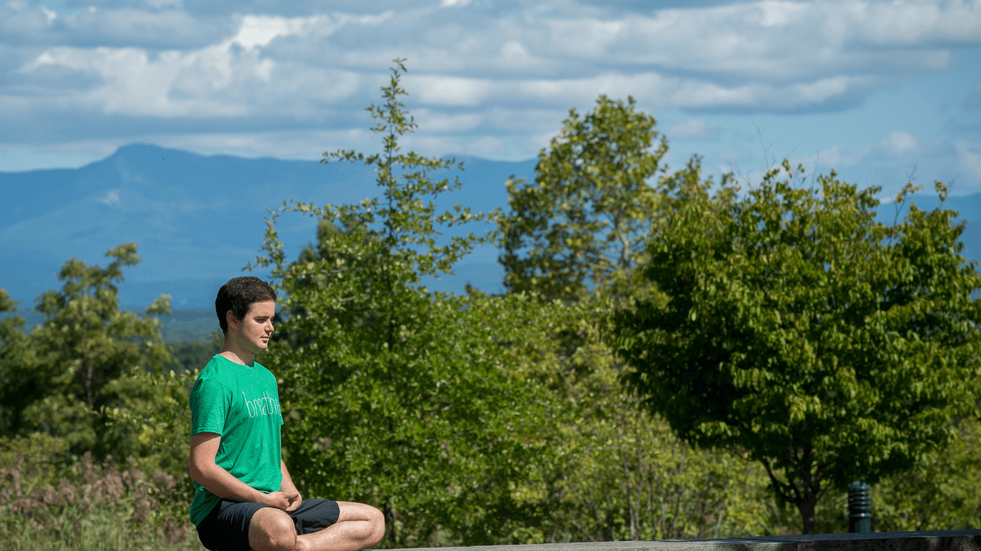 person meditating with mountain in background
