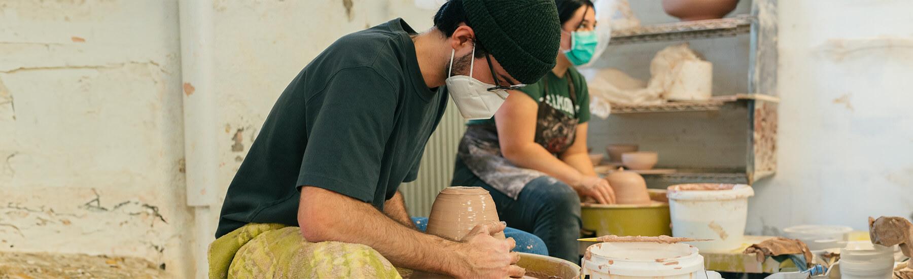 Two people making pottery in a studio