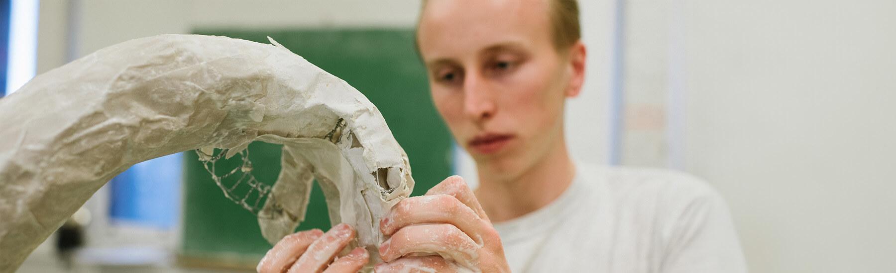 A person molding clay into a sculpture