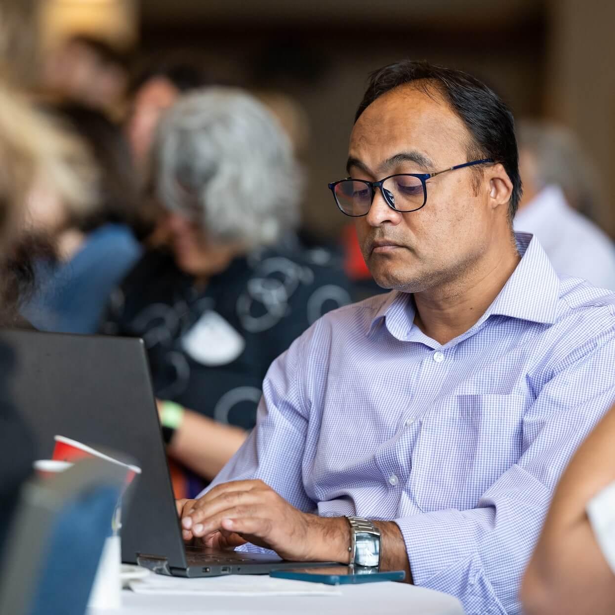 Faculty member types on a laptop