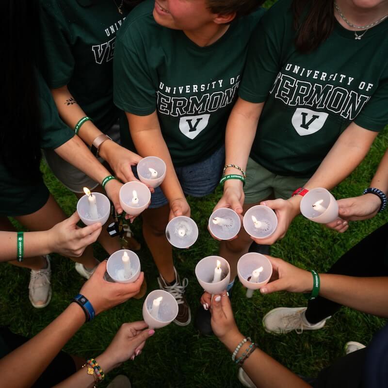 UVM first years gather in a circle holding candles together during convocation