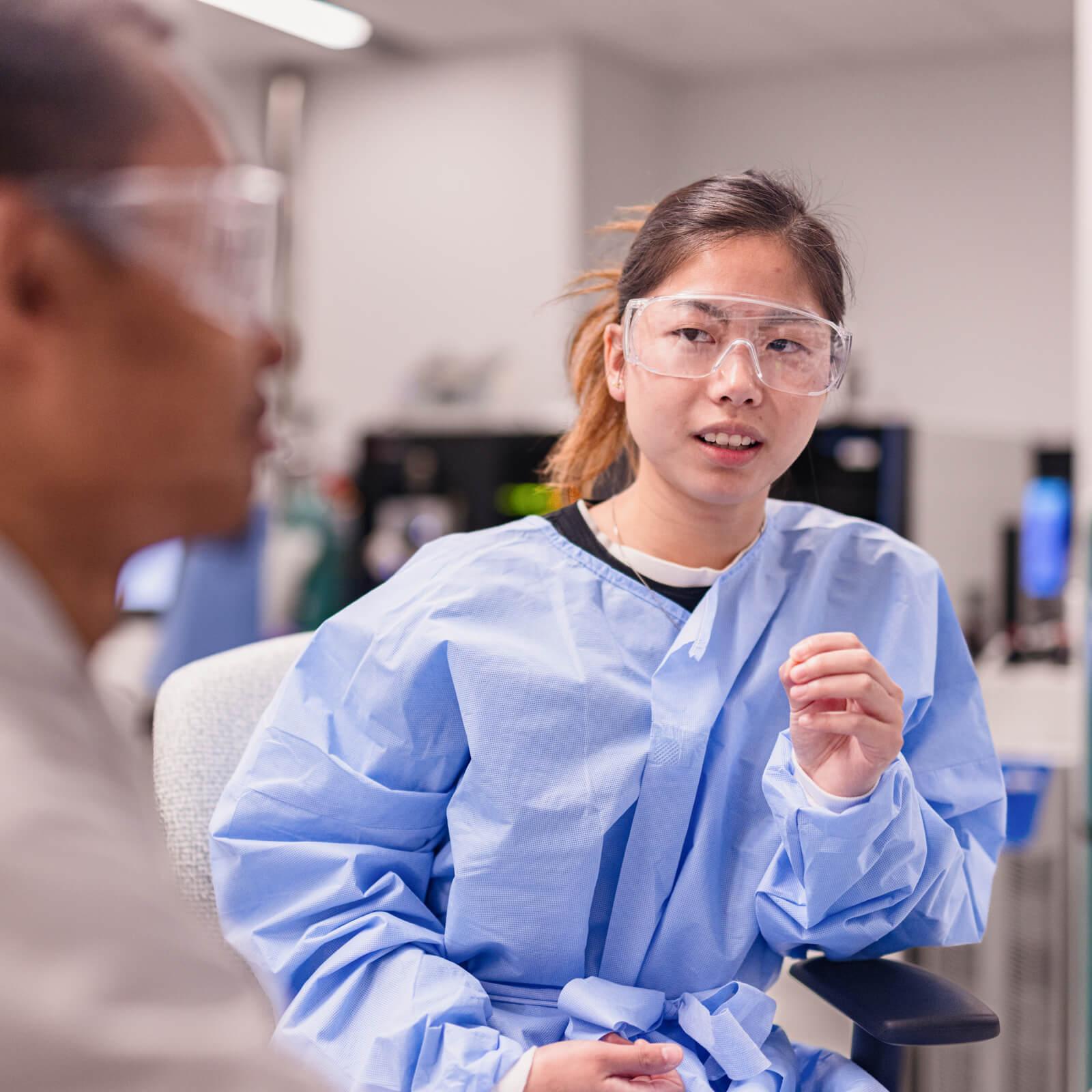 A student wearing scrubs in a laboratory