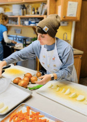 Student assembling chopped produce at a cooking station
