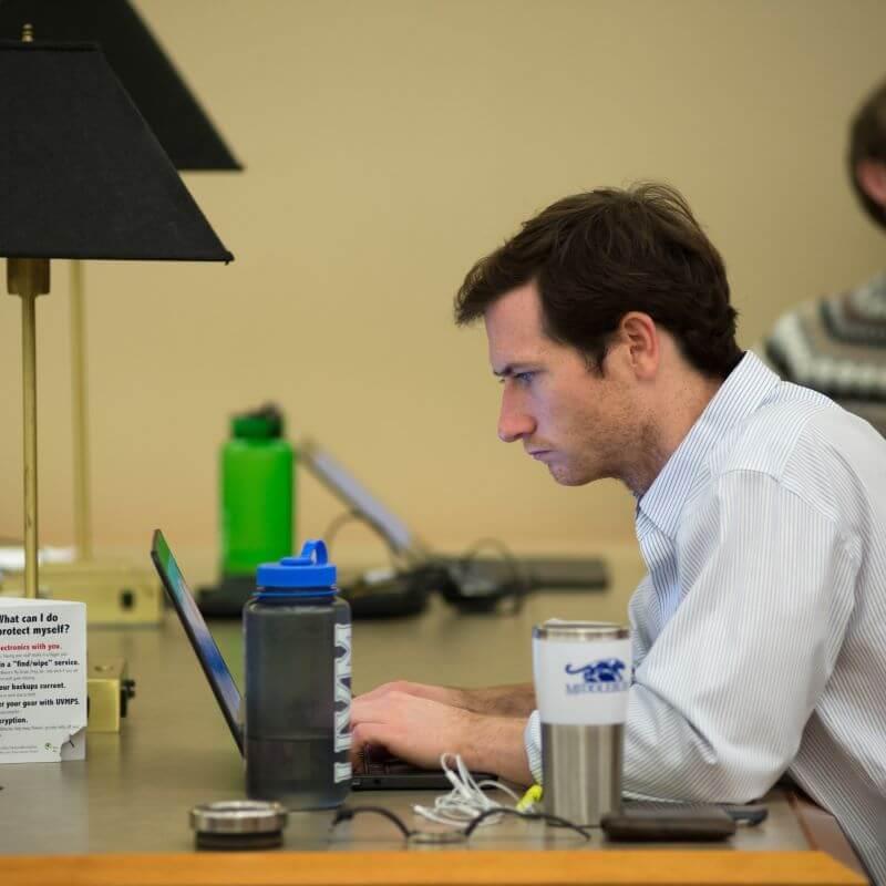 Man sitting at a table working on a laptop