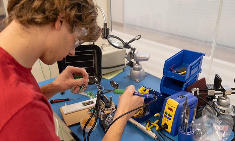 CEMS student solders parts for a prototype he and his team are designing for their senior capstone engineering project