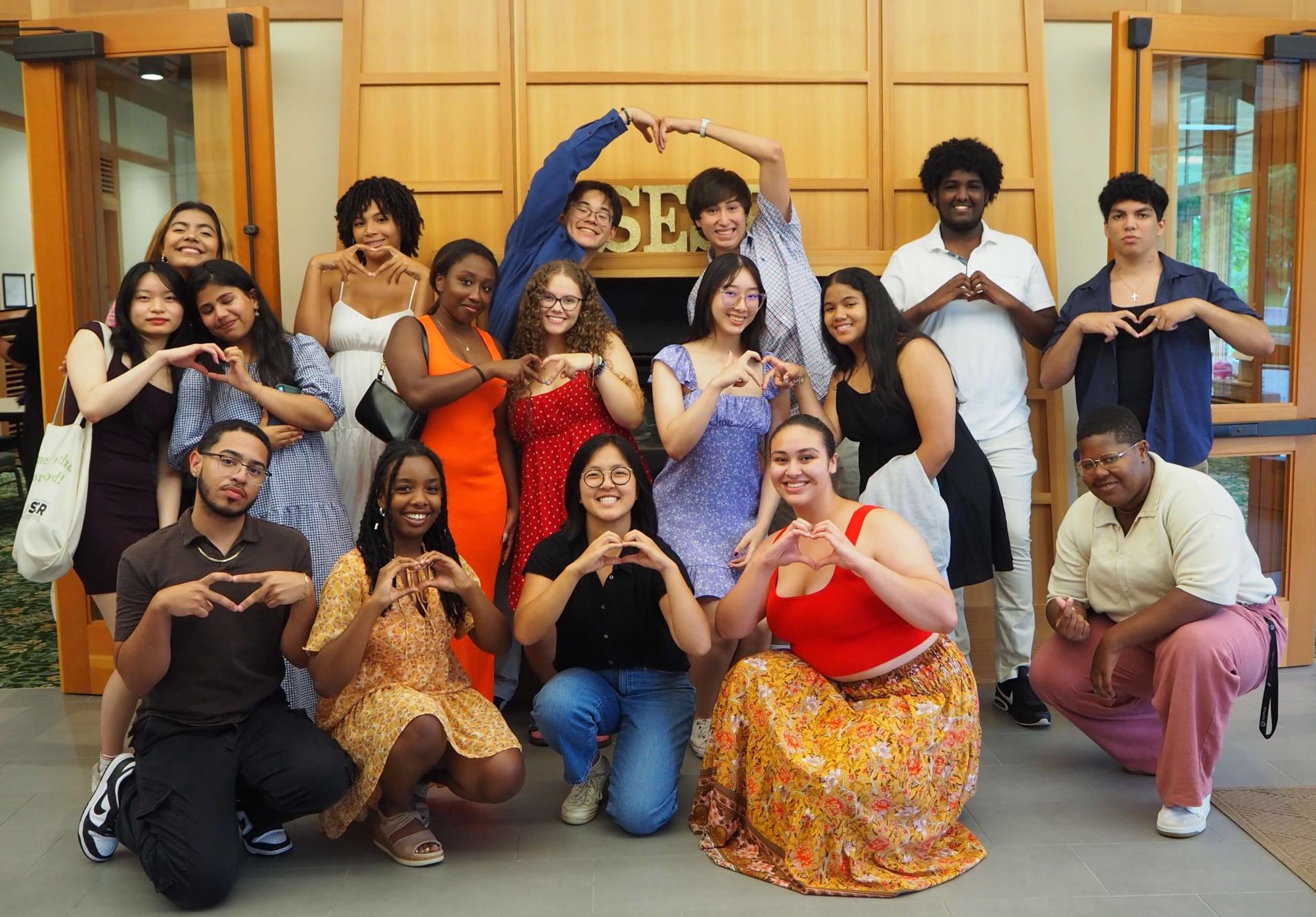 A group of students smiling and making heart shapes with their hands
