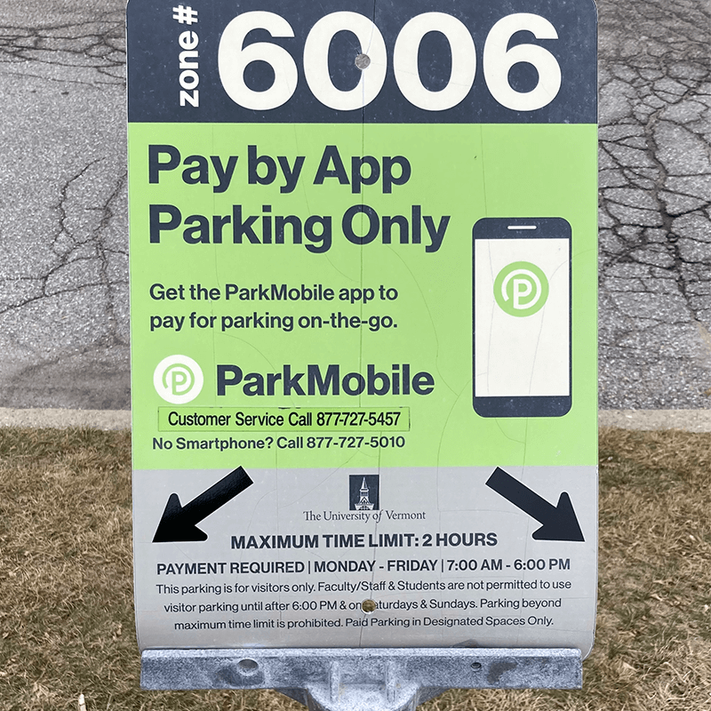 A parking sign on the UVM campus indicating a space that is for visitors only