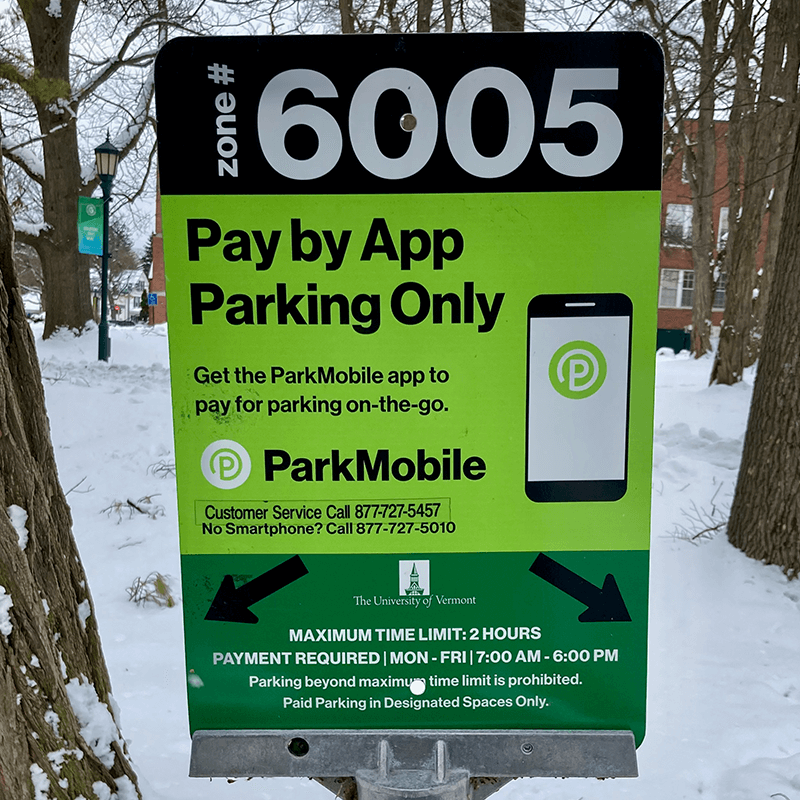 A parking sign on UVM campus for 2 hour pay by app parking