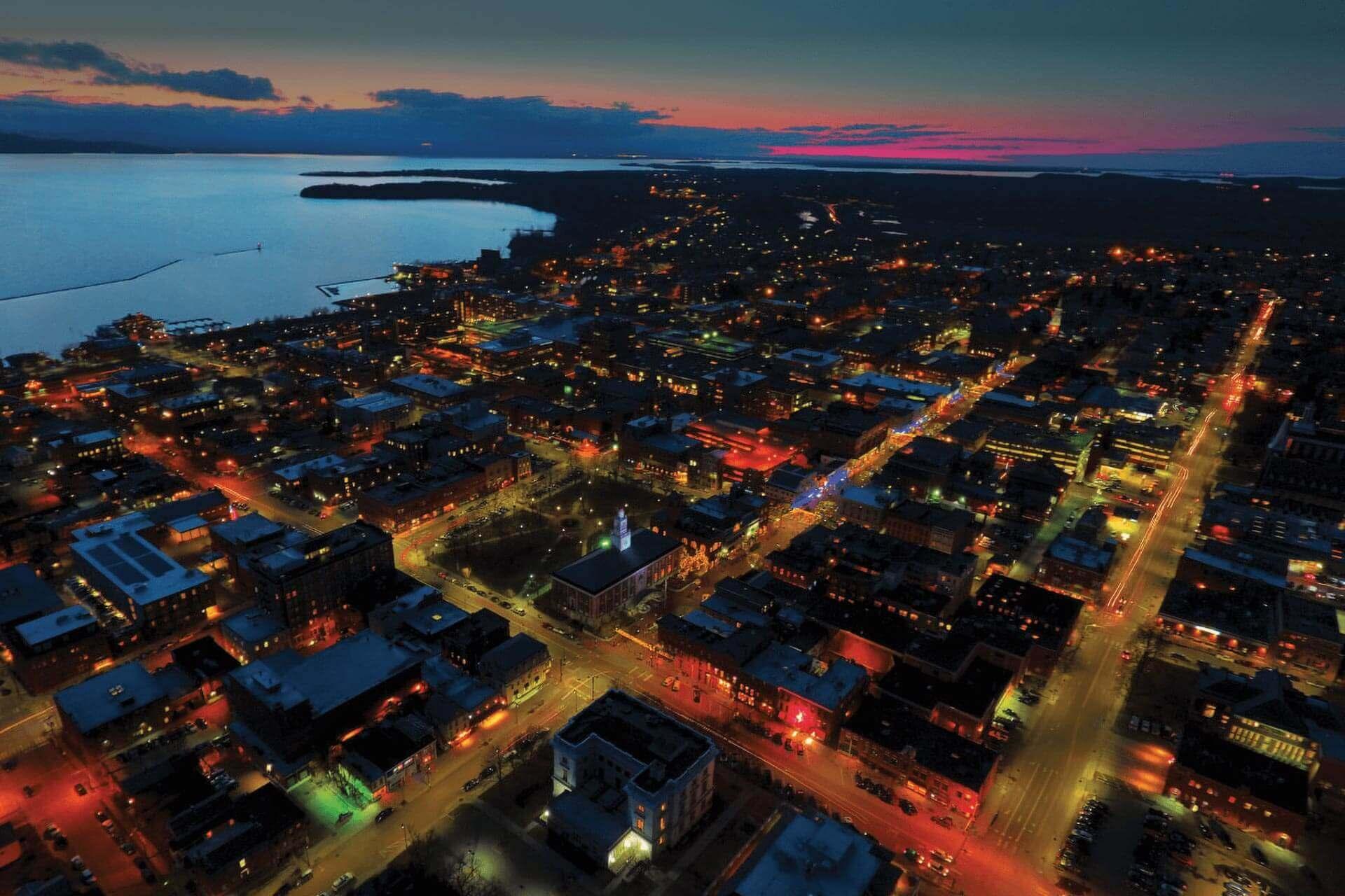 Aerial view of Burlington and the UVM Campus at sunset accented by colorful lights and the lake.