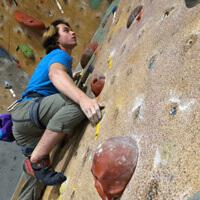 A male student tackles the climbing wall.