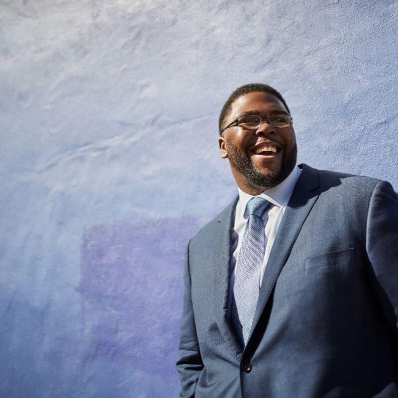 Dr. Anthony Jack leaning up against a purple wall