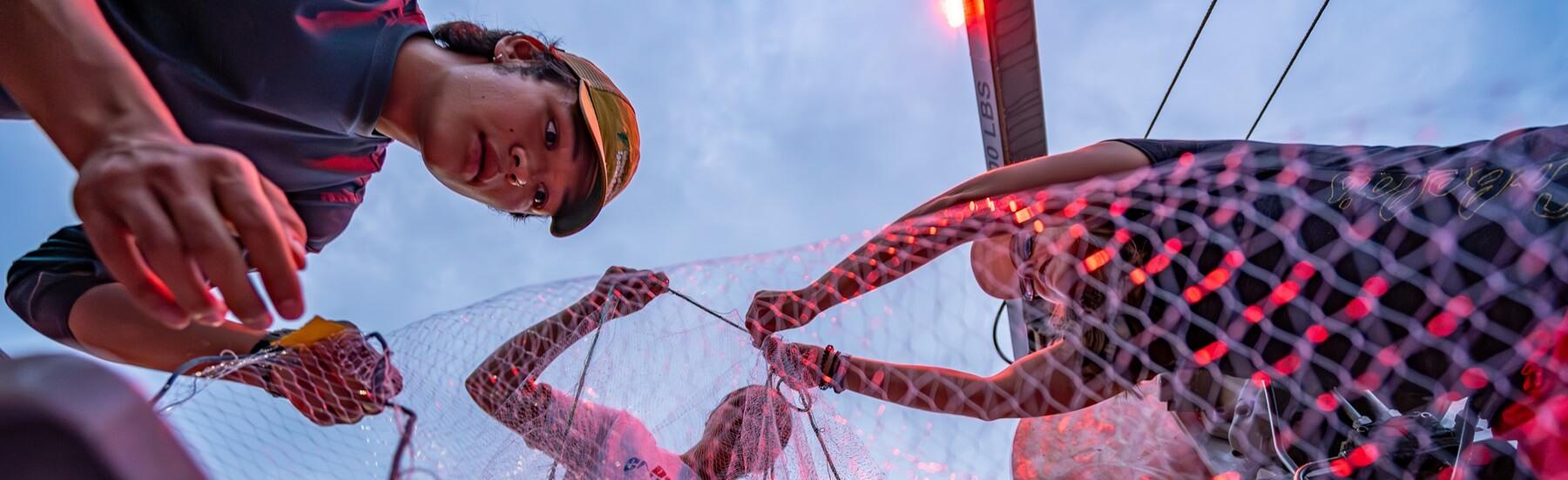 Students working on a boat untangling trawling nets