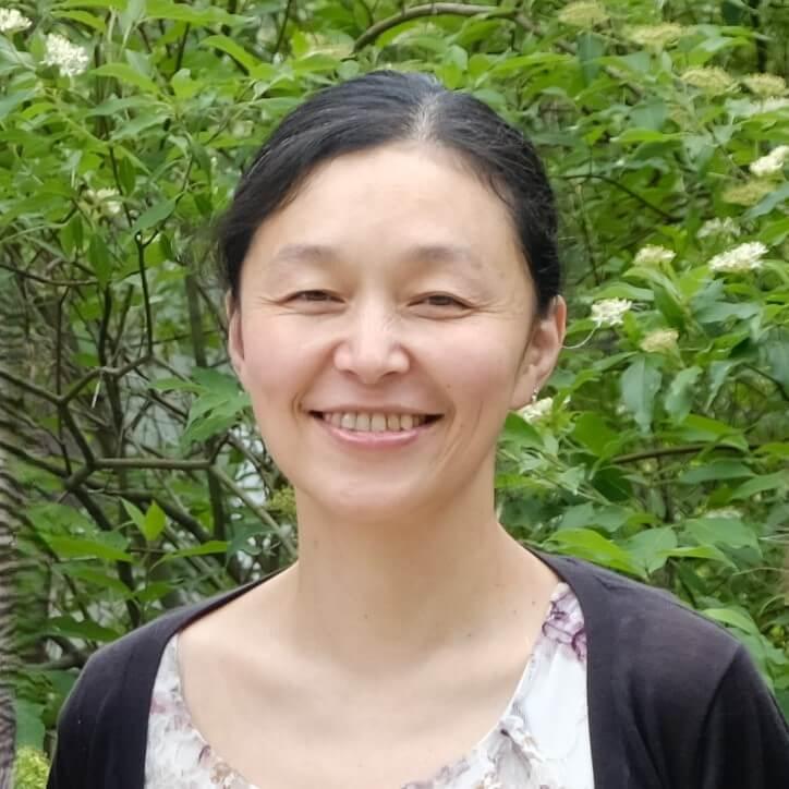 Headshot image of the researcher outdoors, posed in front of green foliage.