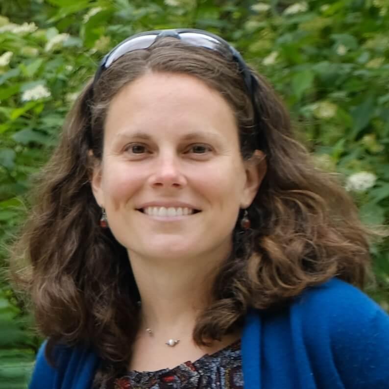 Headshot image of the researcher outdoors, posed in front of green foliage.