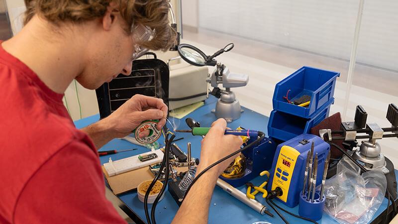 A senior CEMS student solders a component for his capstone design project