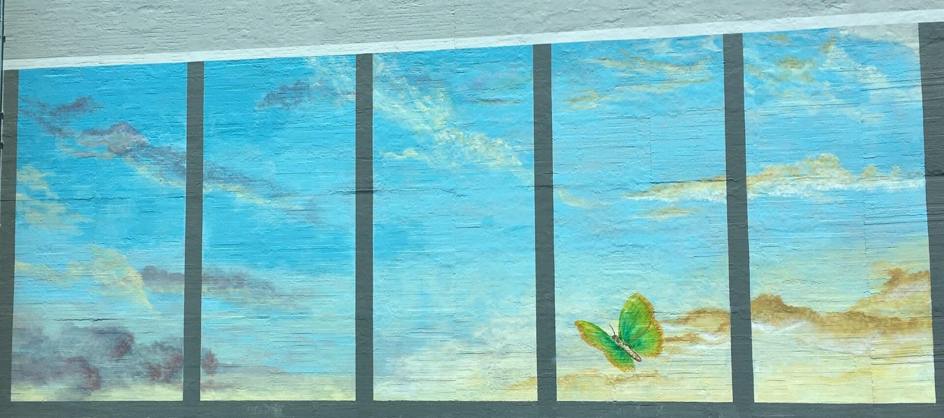 A mural of a butterfly among blue sky and clouds