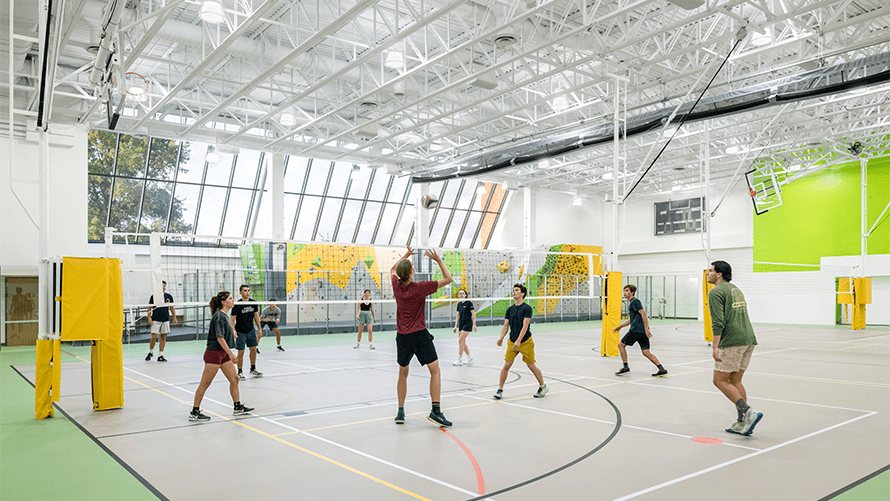 students playing volleyball inside new bright athletic facility