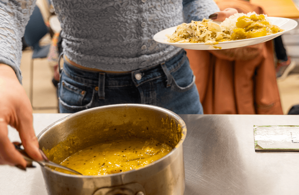 A student serving themselves from a pot of dal