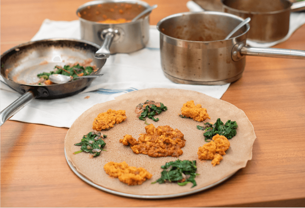 Servings of greens and lentils on injera