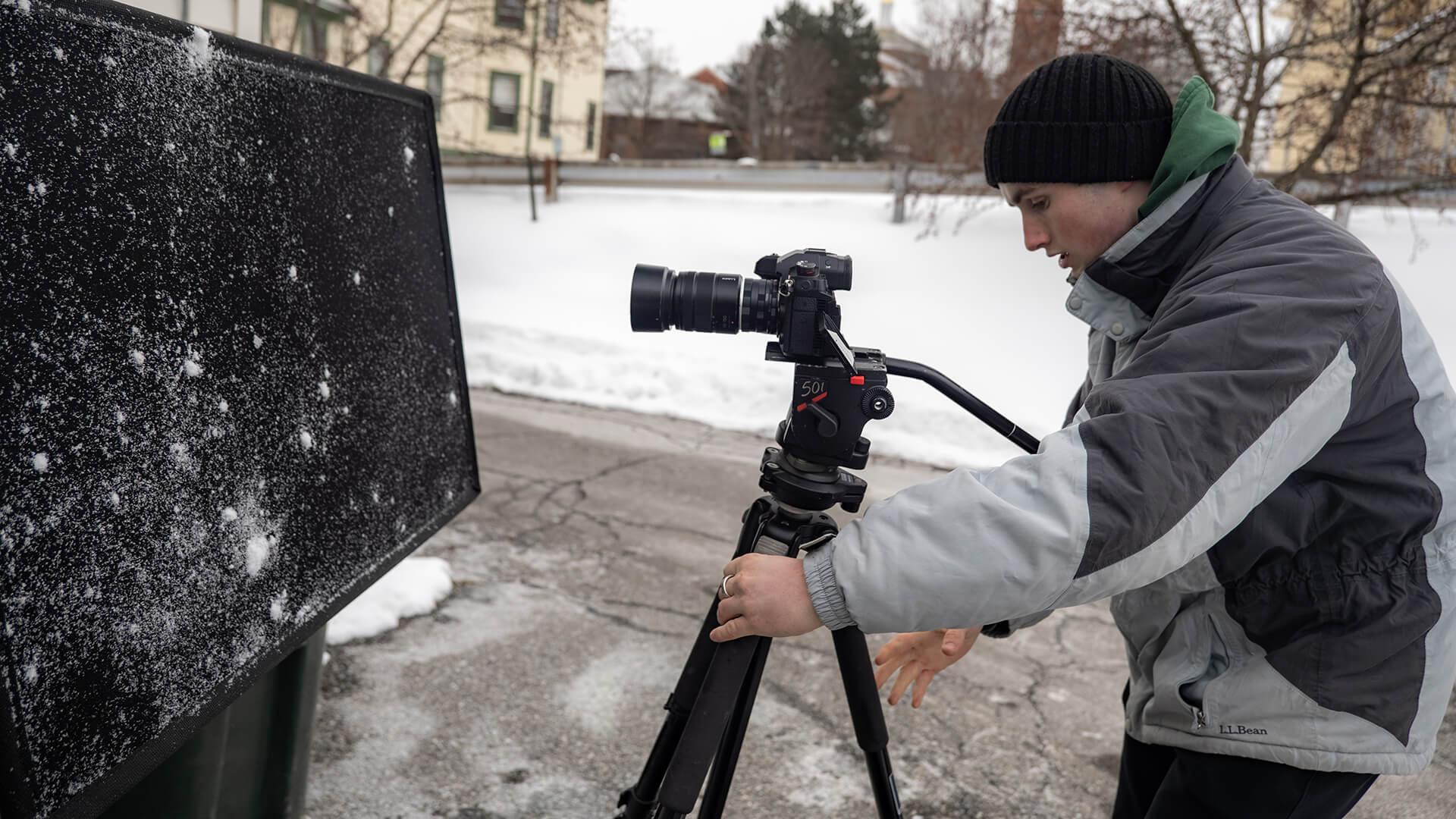 University of Vermont intern for Across the Fence sets up a camera on a tripod