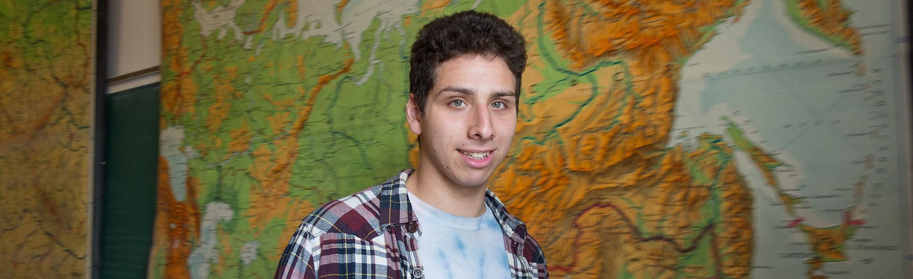 A person standing in front of poster of a map
