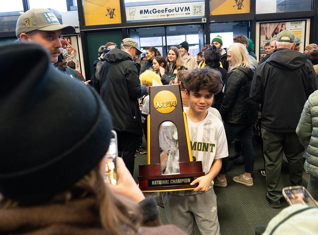 A young fan holds the NCAA Men's Soccer Championship trophy after the UVM Catamounts return home with it.