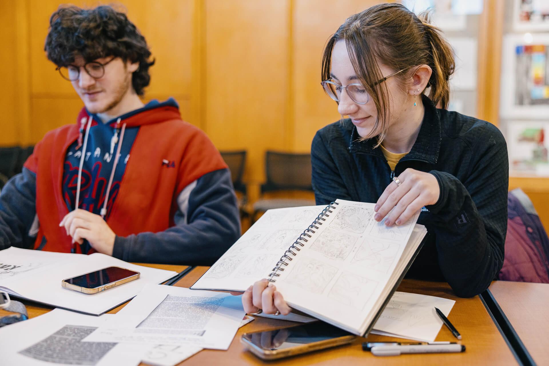 A student holding up their hand-drawn comics