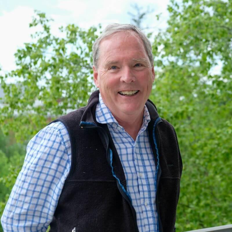 Researcher smiling posed in front of green foliage outside