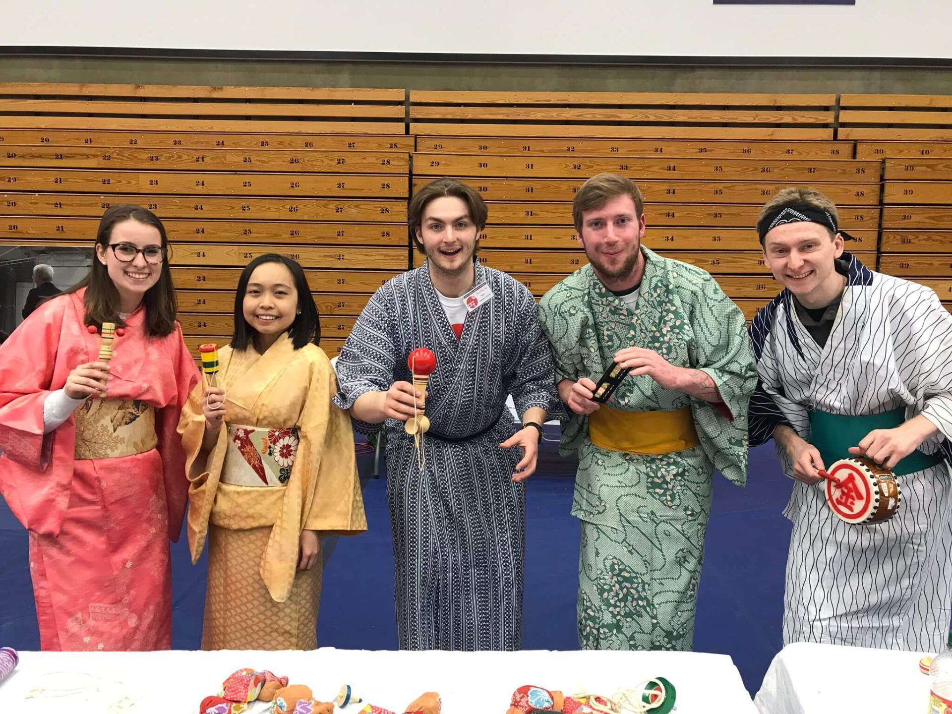 A group of individuals in Japanese dress, smiling and posing together for a photograph.
