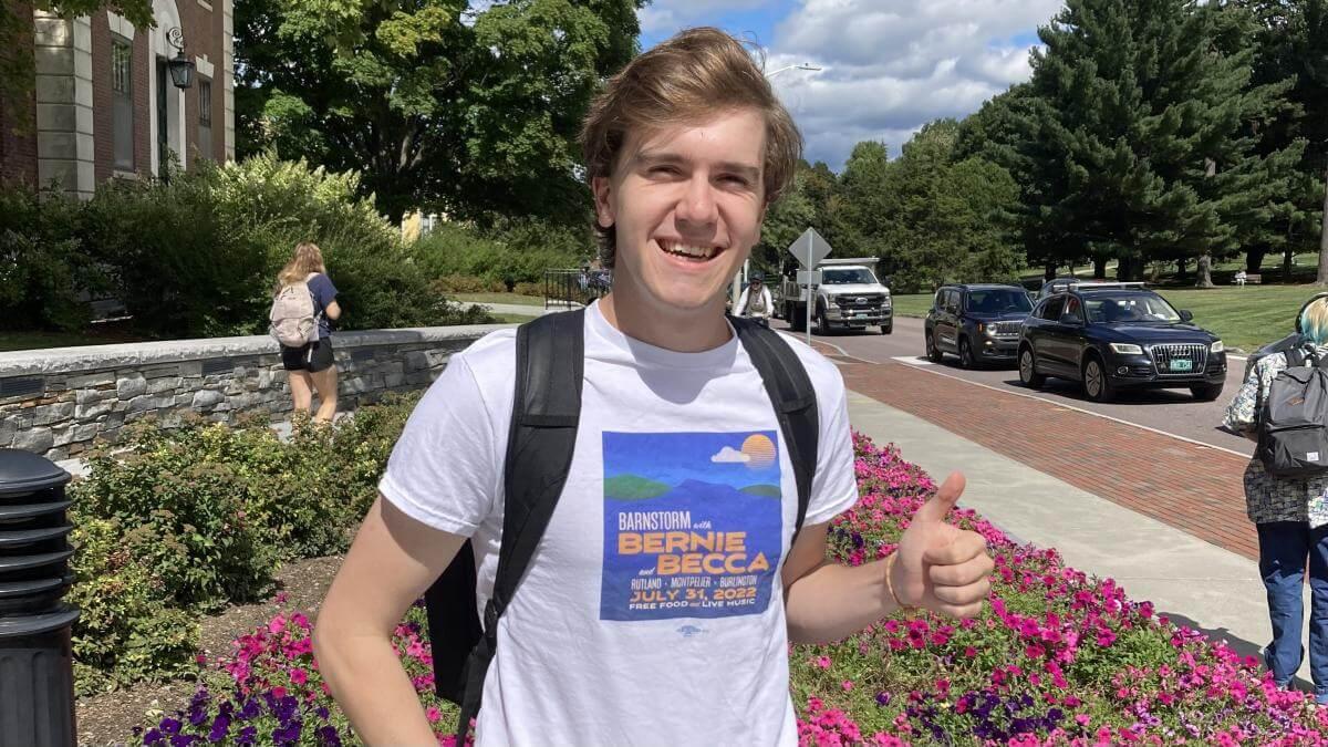 Chris standing outside of the Waterman Building on UVM's campus and giving a thumbs up