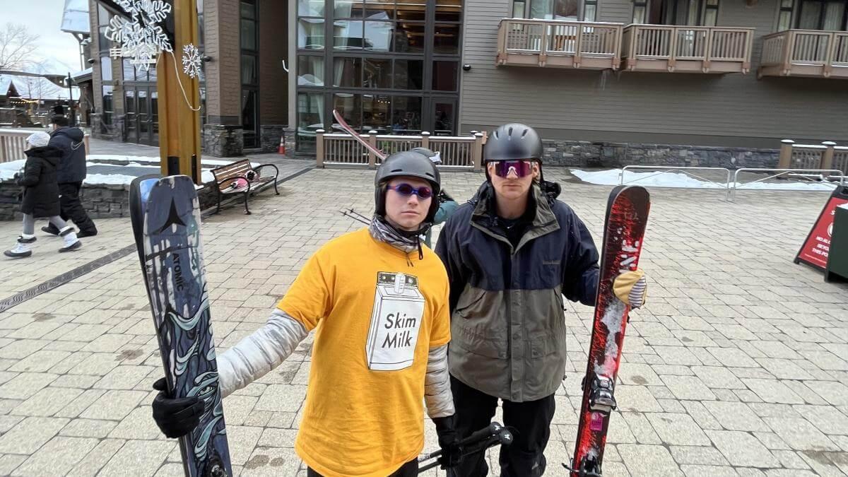 Cole and a friend posing with their skis at a ski resort.