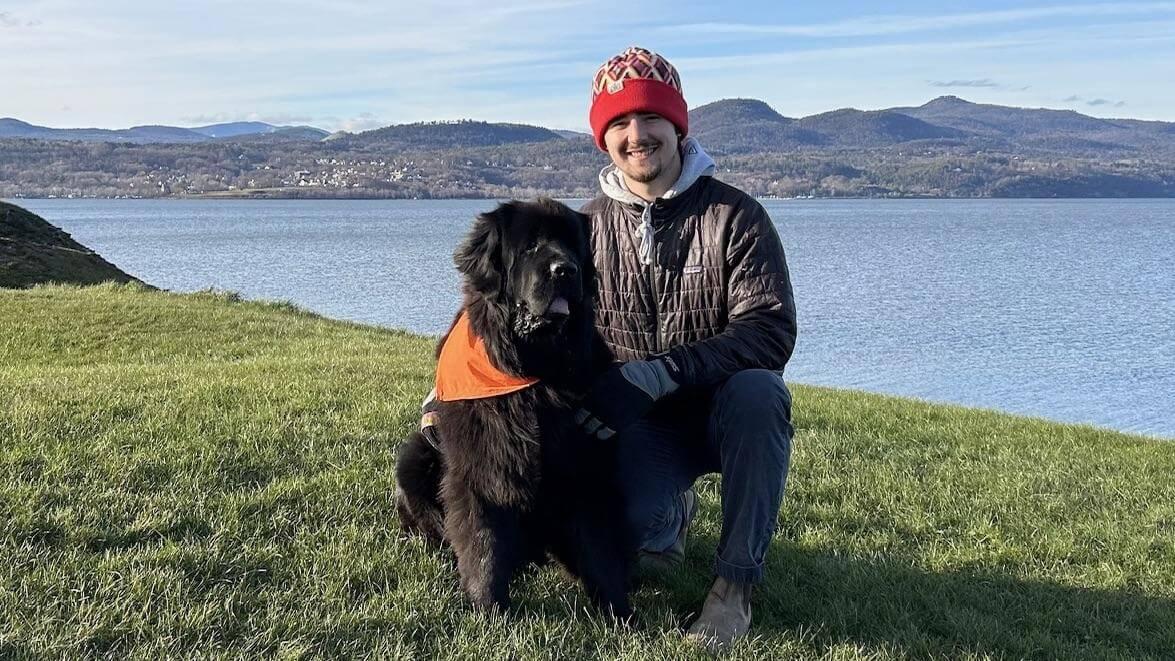 Gus posing outside with his dog, a newfoundland.