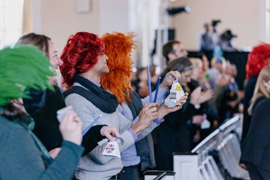 Attendees at the memorial wearing wigs and playing cowbells in the Ira Allen Chapel.