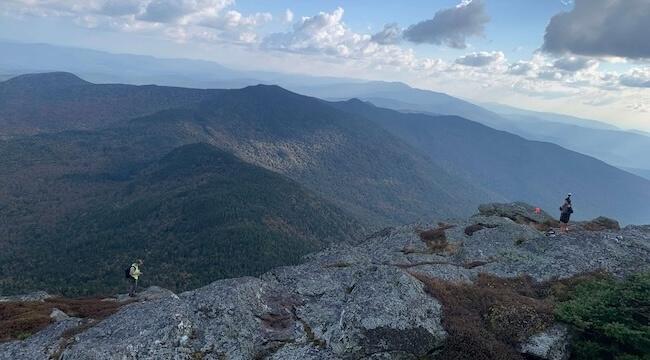 two smallfigures standing on a mountain ridgeline