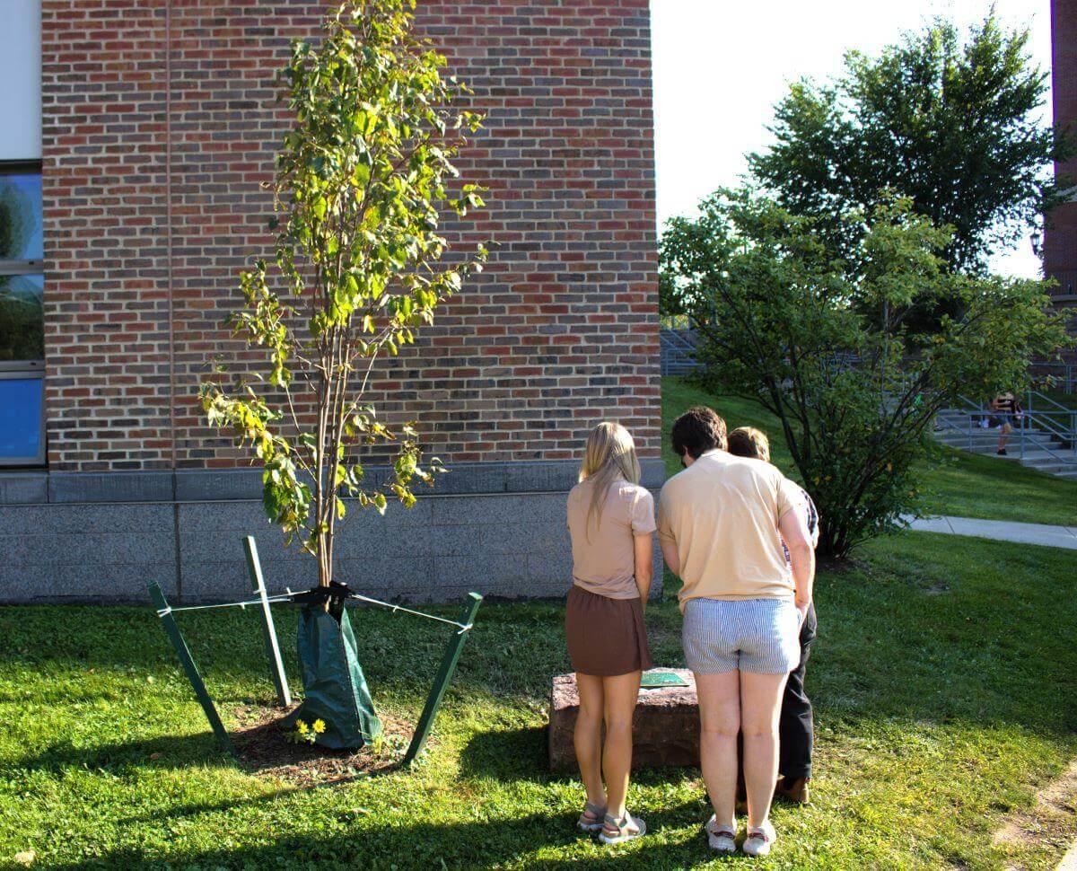 Three members of the Spatial Analysis Lab staff reading the plaque in memory of Jarlath