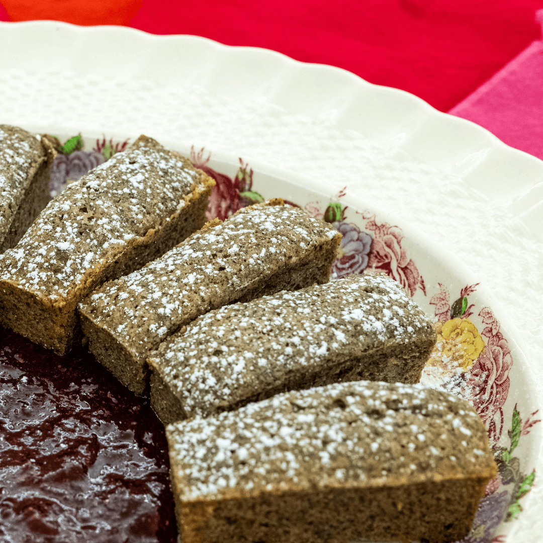 Financiers on a white plate arranged around strawberry compote