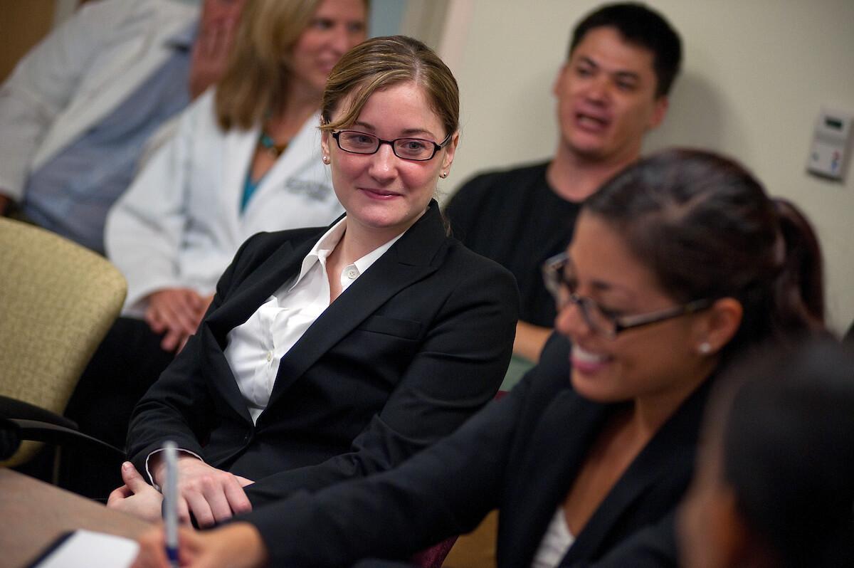  A woman in a business suit seated at a table, engaged in discussion with colleagues