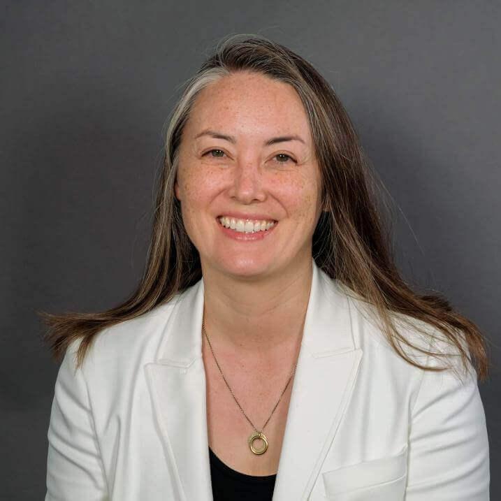 Researcher smiling posed against a grey background