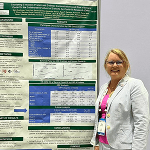Researcher posing to the side of a scientific poster