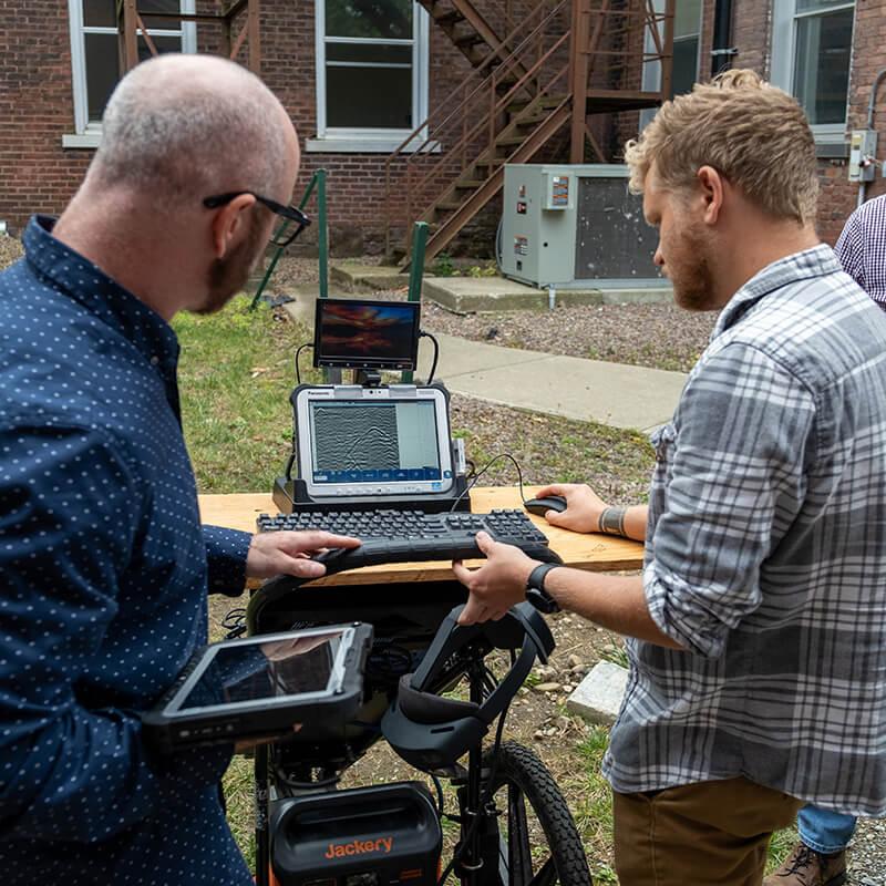 Professor Dylan Burns works with a student on ground penetrating radar equipment
