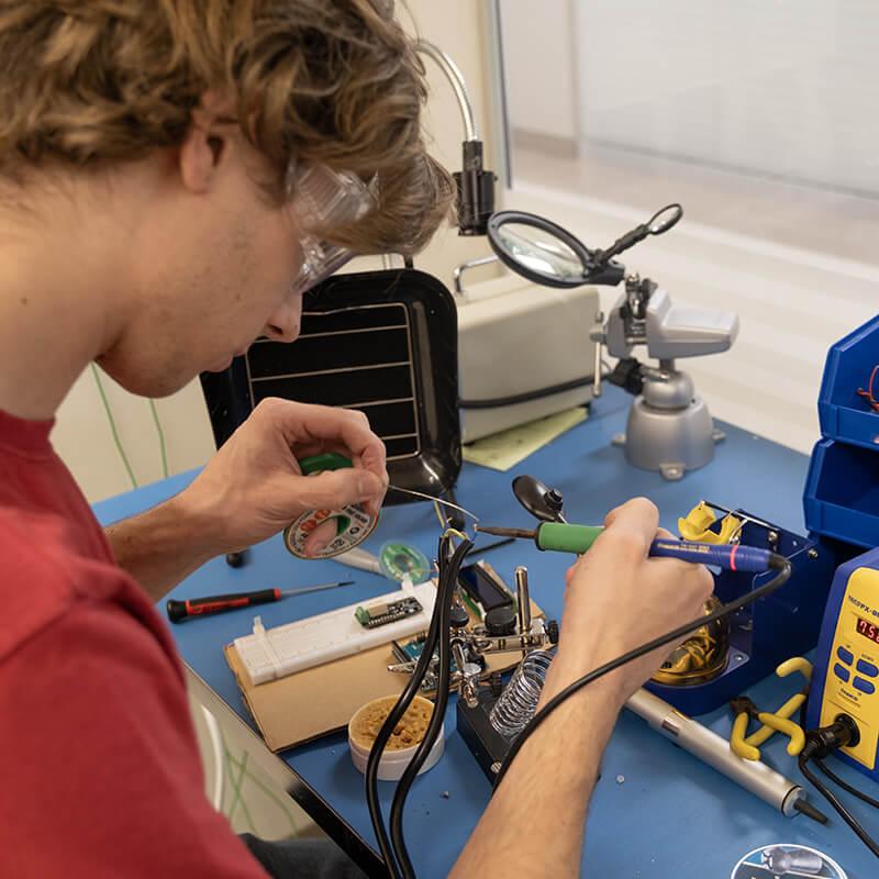 An electrical engineering student soldering on his capstone project