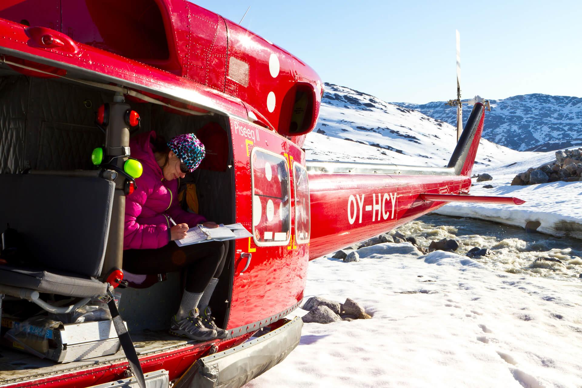 A researcher makes notes while riding in a helicopter in Greenland