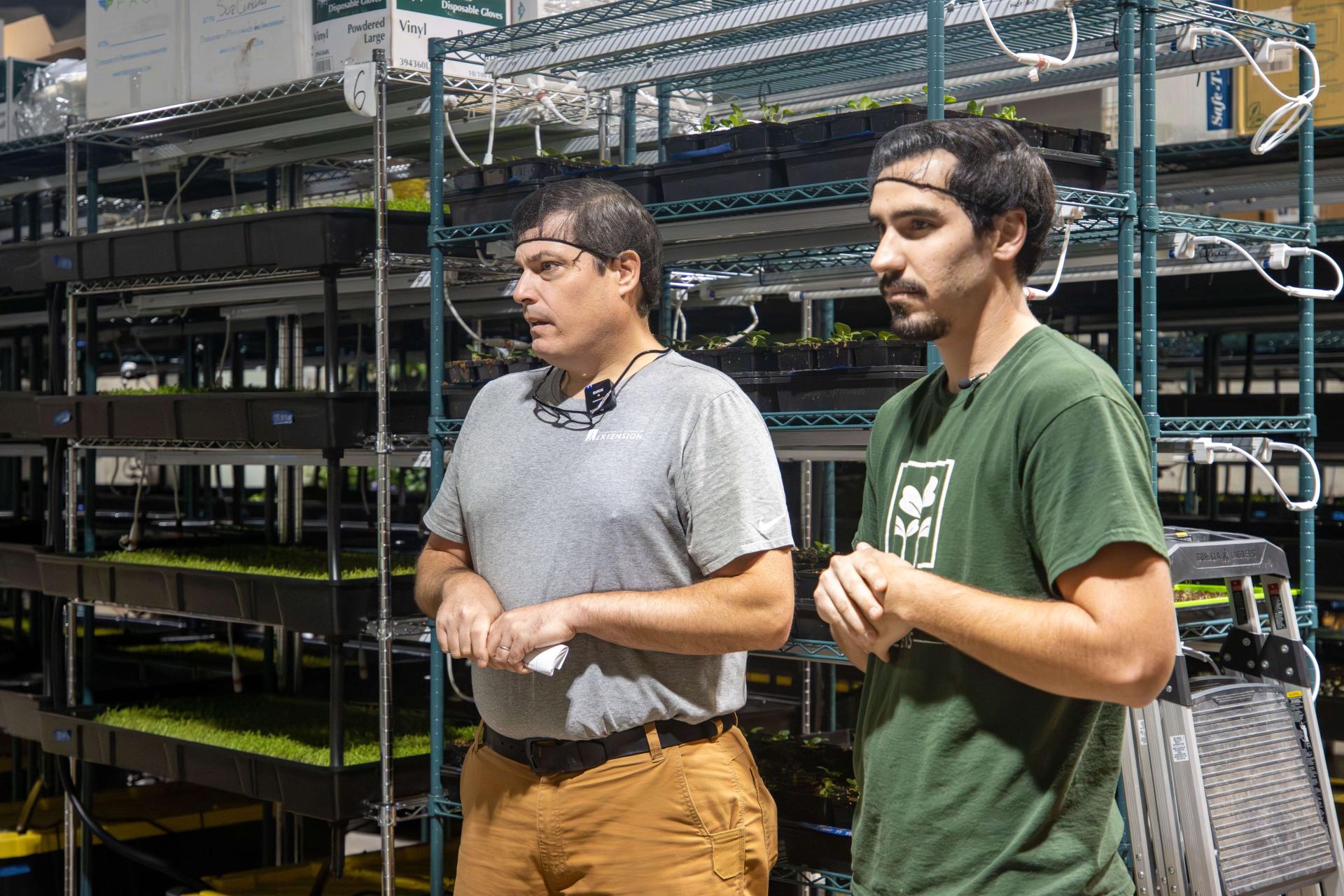 Visitor and worker standing in front of vertical microgreens production racks.