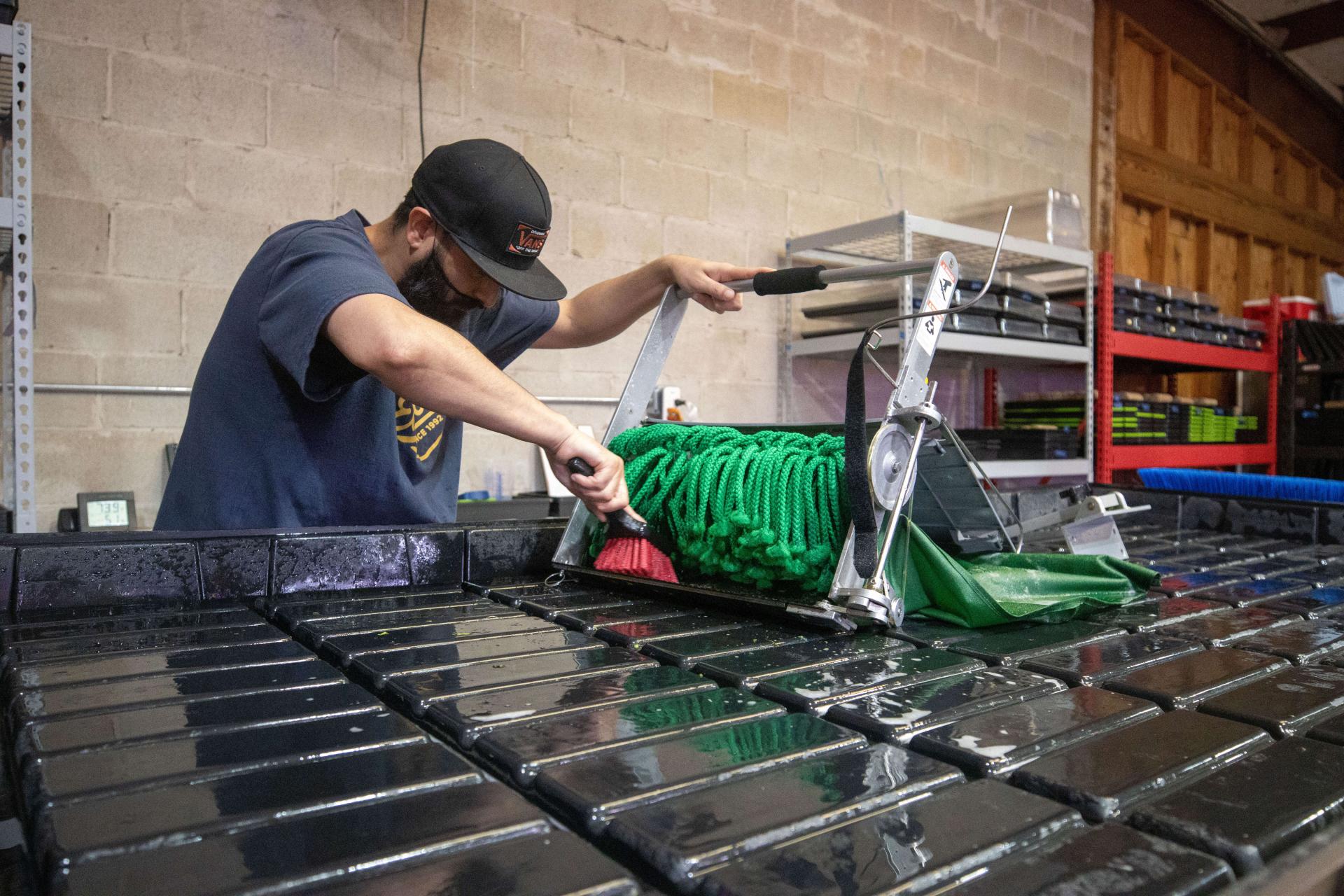 Worker scrubbing the Quick-Cut Greens Harvester with a brush