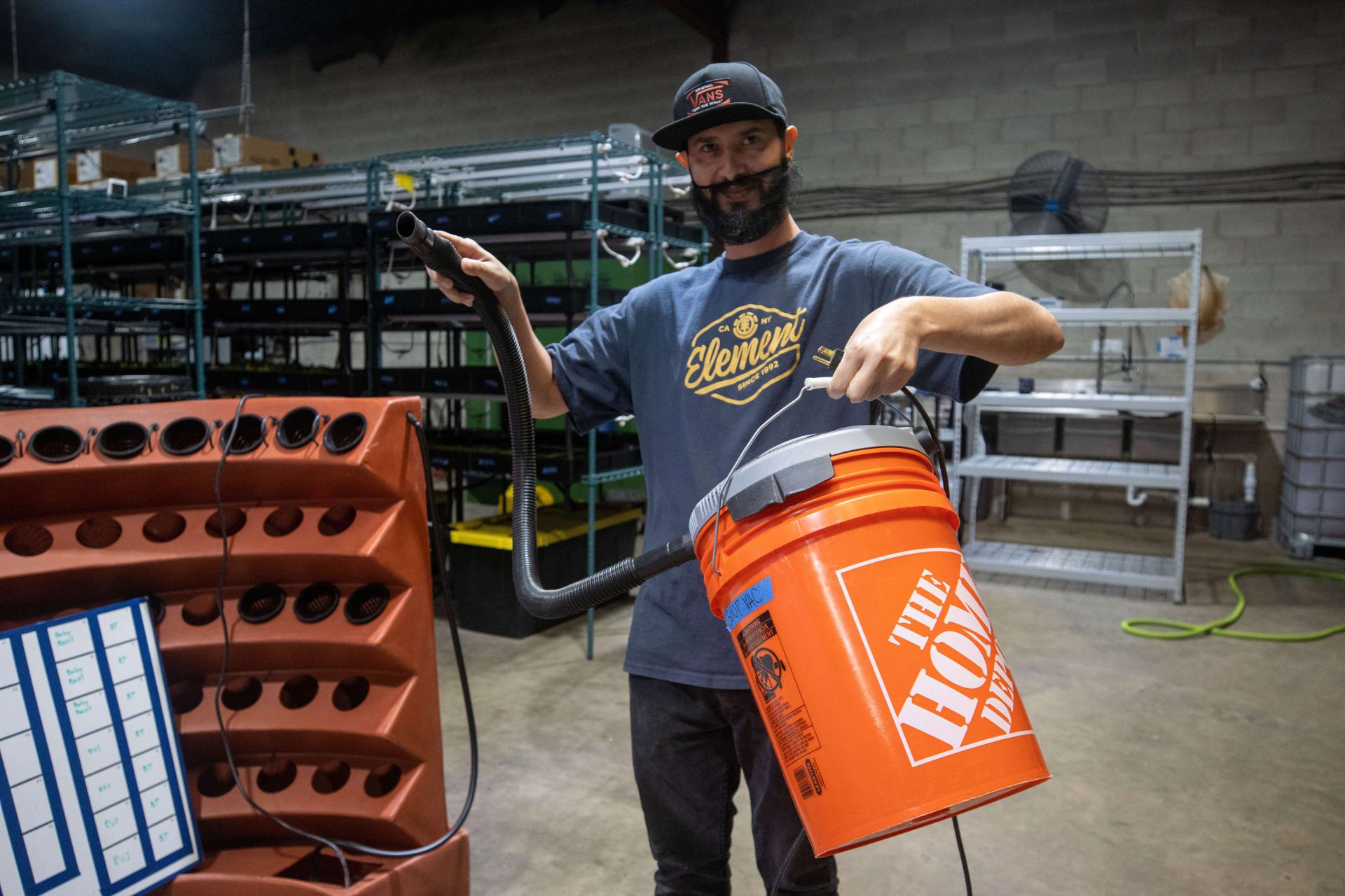 Worker holding a 5-gallon bucket with a shop vac attached to the top.