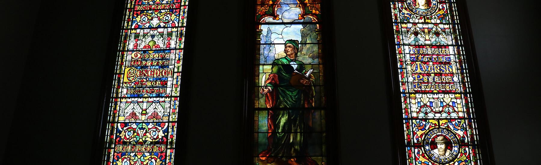 A grand glass window showcasing detailed art, casting colorful reflections in the room