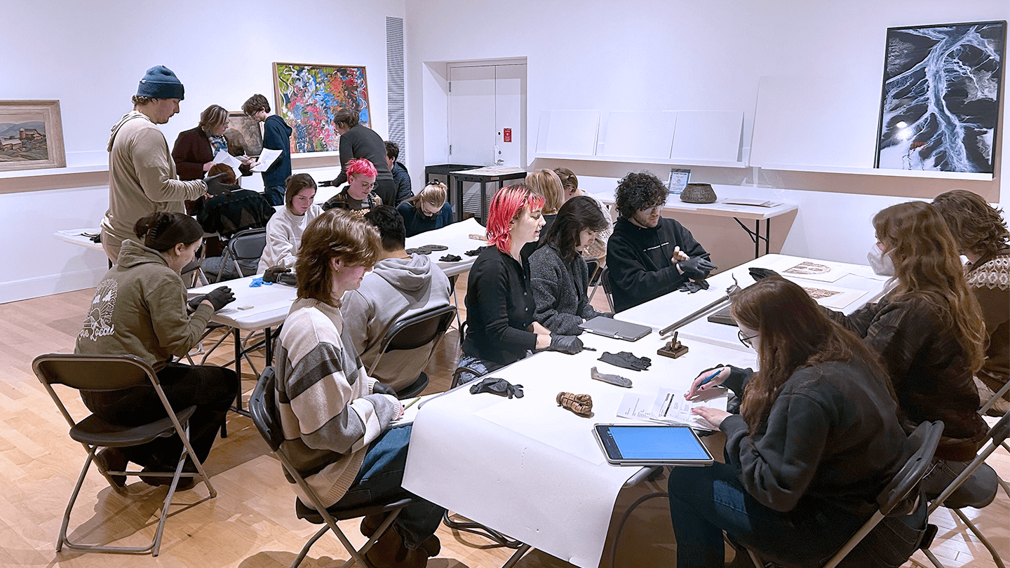 students working with artifacts at tables in the Fleming Museum's Learning Studio