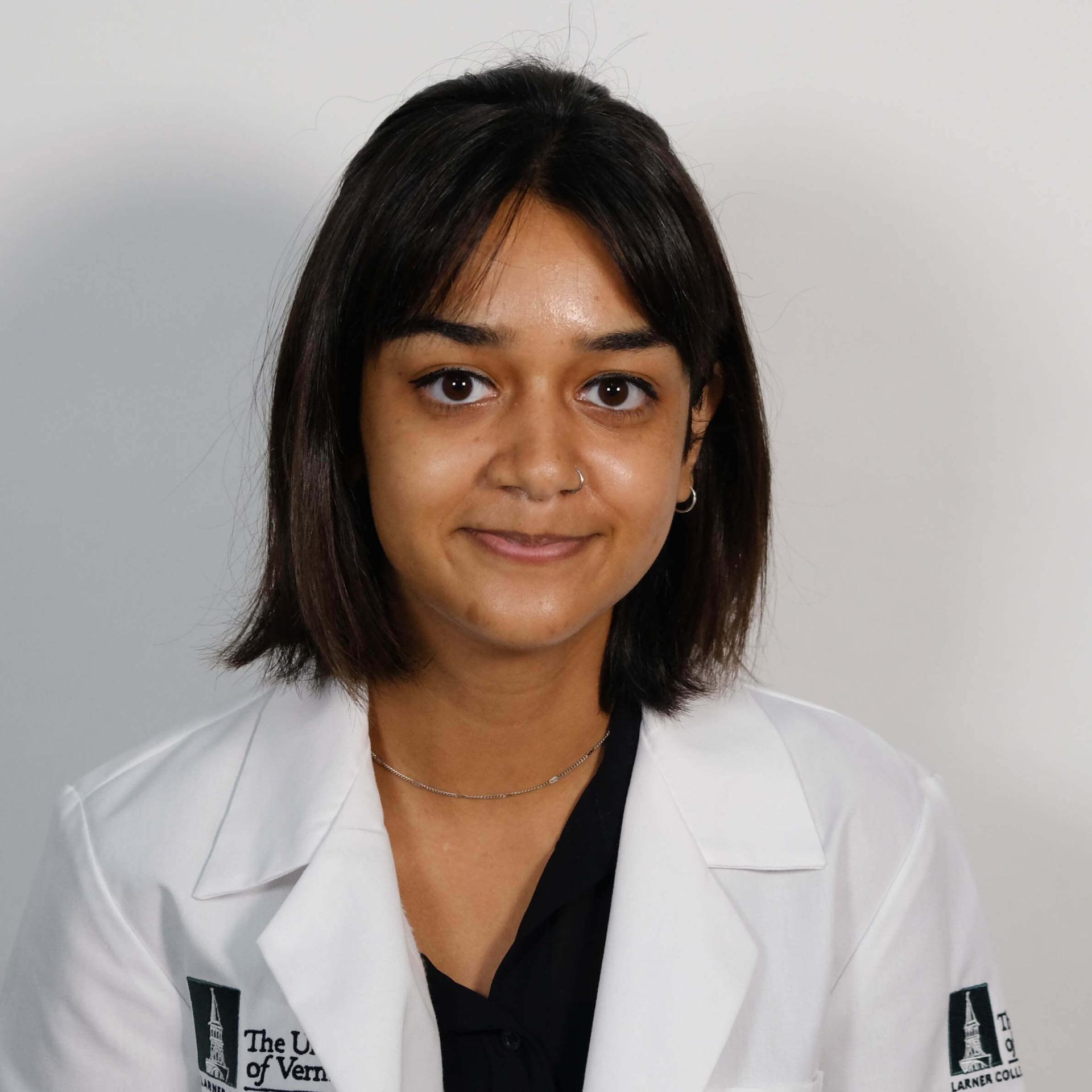 A person with shoulder length hair in a white coat