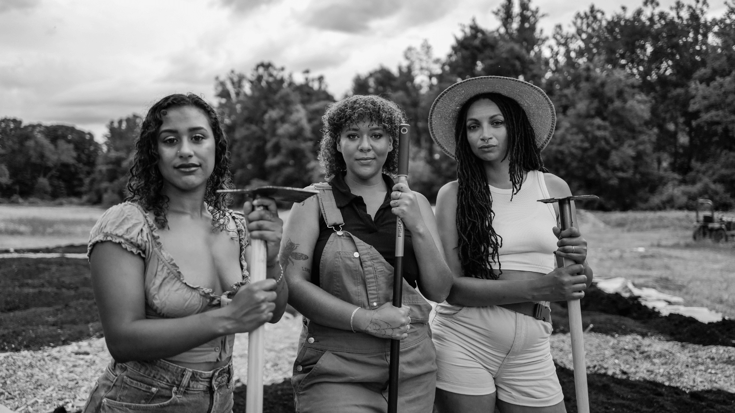 Black and white photograph of three women farmers; Vermont landscape in the background