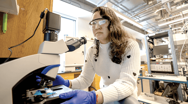 Dr. Ou working in a lab at a microscope